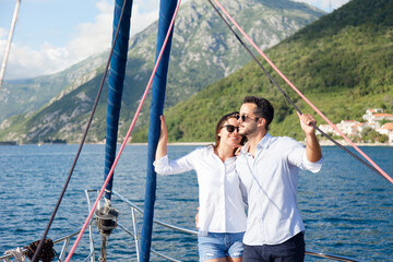 Happy couple in love traveling on yacht at sea. Tourists sailing, enjoying sunny summer vacation. Travelers hugging and relaxing. Intimate romantic date and holidays on sailboat. Lifestyle moment