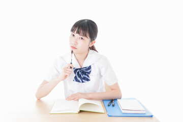 机で勉強をする制服姿の女子学生