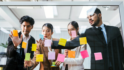 Group of successful Asian businessmen teamwork. Brainstorm meeting with sticky paper notes on the glass wall for new ideas. Using agile methodology for business in a tech start-up office. - 780640430
