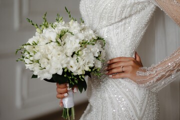 Beautiful bride in an elegant white gown holding a stunning bouquet of white flowers