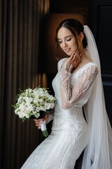 Elegant bride in a white dress holding a bouquet of white flowers