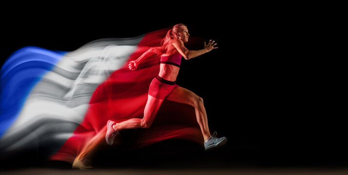 Dynamic image of competitive young woman, runner in motion, running on black background with flag of France element. Concept of professional sport, competition, tournament. Banner. Sport event