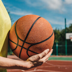 Basketball player is holding basketball ball on a court, close up photo