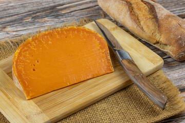 tranche de fromage français : mimolette extra vieille, en gros plan, sur une planche à découper - obrazy, fototapety, plakaty