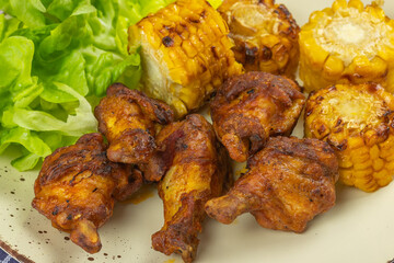 pilons de poulet et maïs grillé dans une assiette