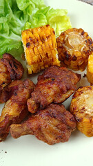 pilons de poulet et maïs grillé dans une assiette	