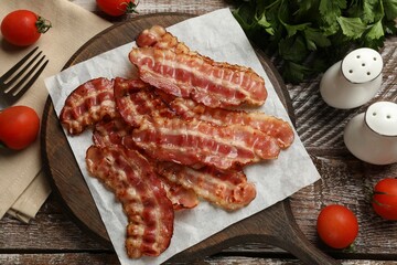 Fried bacon slices, tomatoes, parsley and spices on wooden rustic table, flat lay