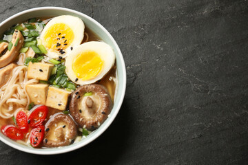 Noodle soup. Bowl of delicious ramen on black table, top view. Space for text