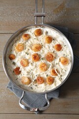 Delicious scallop pasta in pan on wooden table, top view