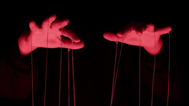 The puppeteer controls the puppets in the theater in red neon light close-up. Managing people at work, in politics and government. Action control