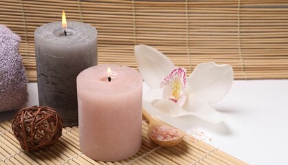 Fototapeta na wymiar Composition with spa products, beautiful flower and burning candle on white table