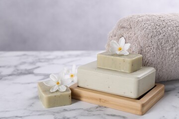 Fototapeta na wymiar Spa composition with soap, flowers and towel on white marble table