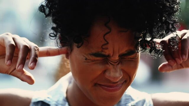 Young Woman Shaking Head Not Wanting to Listen by putting fingers inside ears, muting noise from outside- stubborned reaction wanting to ignore warnings