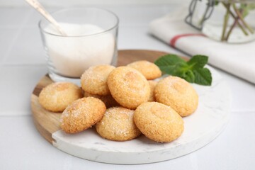 Tasty sweet sugar cookies, milk and mint on white tiled table, closeup