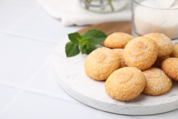 Tasty sweet sugar cookies, milk and mint on white tiled table, closeup. Space for text