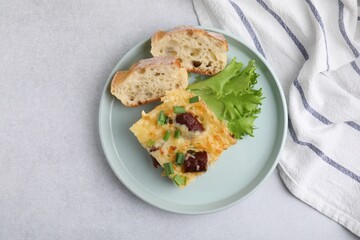 Tasty sausage casserole with green onion and bread on light grey table, top view