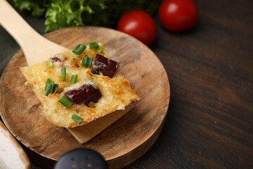 Spatula with piece of tasty sausage casserole on wooden table, closeup. Space for text