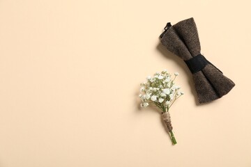 Wedding stuff. Stylish boutonniere and bow tie on beige background, top view. Space for text - obrazy, fototapety, plakaty