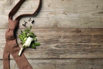 Wedding stuff. Stylish boutonniere, cufflinks and tie on wooden table, flat lay. Space for text
