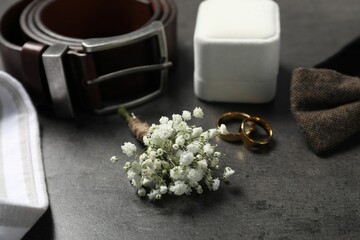 Wedding stuff. Composition with stylish boutonniere on black table, closeup - obrazy, fototapety, plakaty