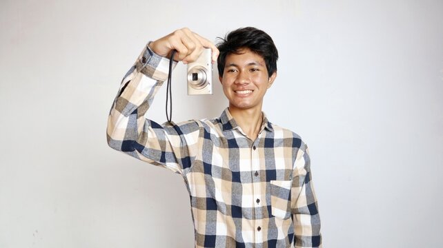 Handsome young Asian man happily taking photos using pocket camera