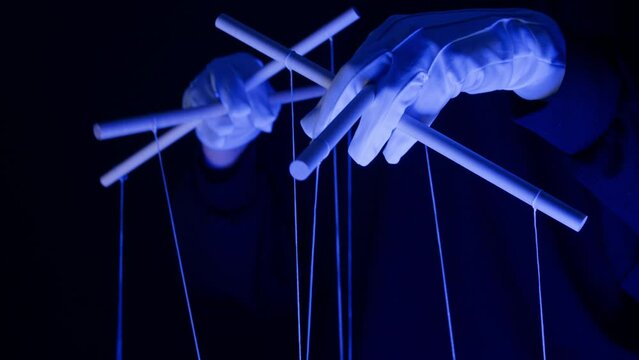 The puppeteer controls the puppets in the theater in blue neon light close-up. Managing people at work, in politics and government. Action control