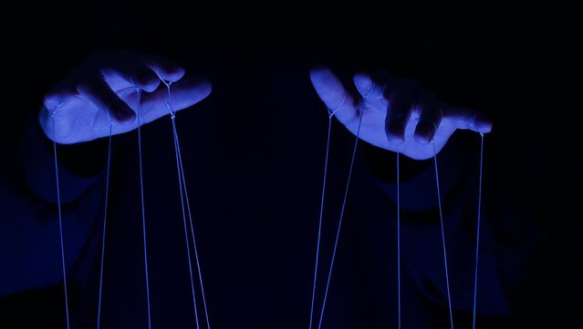 The puppeteer controls the puppets in the theater in blue neon light close-up. Managing people at work, in politics and government. Action control