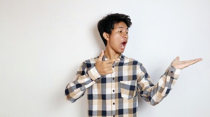 shocked young Asian man posing pointing at his palm with an isolated white background