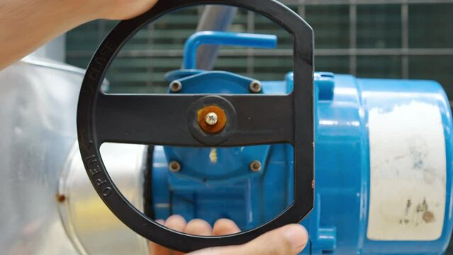 Hands close-up of male technical foreman inspects maintenance turning cut-off valve at plant, Emergency, plumbing and electrical systems on the roof of a building