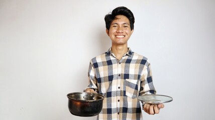 smiling young asian man posing holding a pan