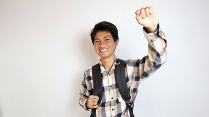 happy young asian man posing raising his hands enthusiastically and holding a bag on an isolated white background