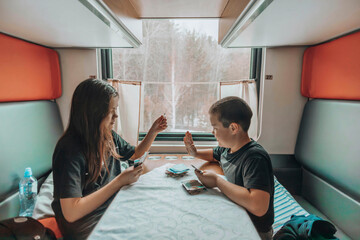 Sibling Bonding Time : In the cozy train compartment, two young individuals engage in a playful...