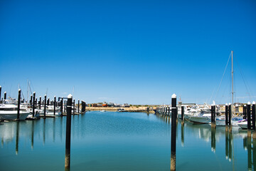 Fototapeta premium The Exmouth boat harbour, a marina on North West Cape, Western Australia. With yachts and sailing boats. Reflection in the water