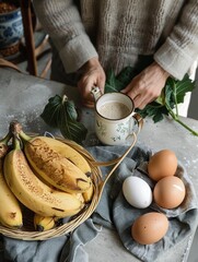 Person pouring milk into a cup with bananas and eggs on a table, depicting a cozy, rustic breakfast scene.