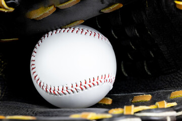 white baseball squeezed in black baseball glove