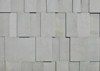 External wall made of horizontal gray granite tiles assembled vertically in relief.  Abstract, background and texture.