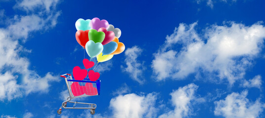 banner with the image of a shopping cart containing decorative hearts and heart-shaped balloons against the sky