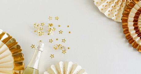 Birthday background top view with champagne bottle, golden stars decoration and paper decor on white backdrop. Copy space. Banner. Holiday, party, wedding , christmas background.