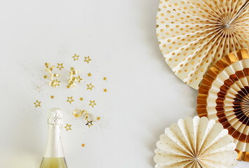 Birthday background top view with champagne bottle, golden stars decoration  and paper decor on white backdrop. Copy space. Holiday, party, wedding background.