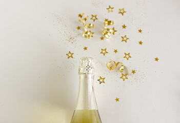 Champagne bottle and golden stars decorationtop view on white backdrop. Copy space. Birthday,...