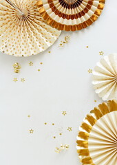 Birthday background template mock up  top view with colden fan paper decor and gold stars confetti on white backdrop. Copy space. Holiday, wedding, party background.