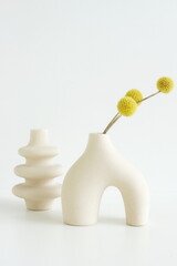 Modern beige ceramic vases with dry  grass on white table near white wall.  Minimal Scandinavian...