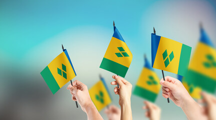 A group of people are holding small flags of Saint Vincent in their hands.