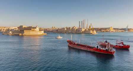 Several large red tankers on the roadstead of Valletta on a sunny morning.