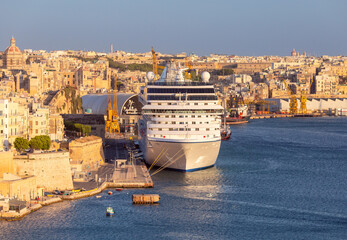 A large white tourist boat near the Valletta pier on a sunny morning.