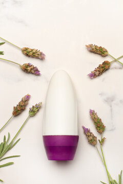 Desodorante antitranspirante junto a unas ramitas de lavanda natural sobre un fondo de m&aacute;rmol blanco. Vista superior y de cerca. Copy space. Formato vertical