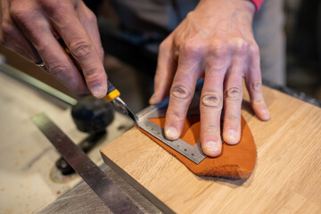 Man hands cutting leather skin. Master shoemaker pro cobbler guy palms measures right amount, uses ruler tool retractable construction knife. Process of working with natural leather in workshop