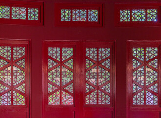 close up of red wood framed windows with sheer covering with copy space