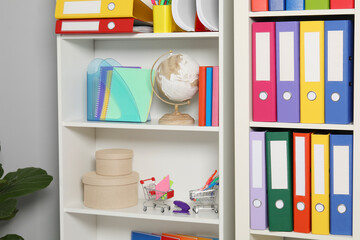 Colorful binder office folders and other stationery on shelving unit indoors