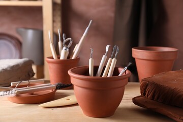 Set of different clay crafting tools on wooden table in workshop